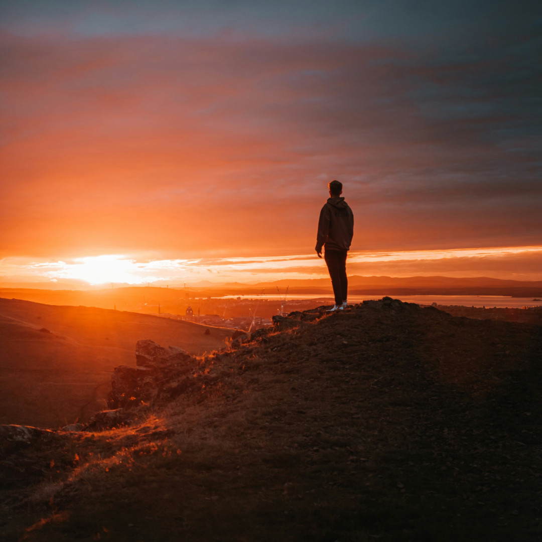 A person in deep contemplation of a beautiful golden sunset representing personal reflection